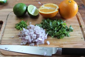 Before blending the marinade, dice the pepper, shallot, and cilantro. Halve the oranges and limes so that you can squeeze the juice into the bowl. 