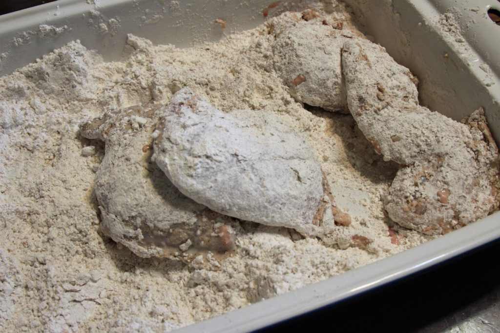 Dredge the rabbit in the seasoned flour mixture. Resting the dredged rabbit for five to 10 minutes helps prevent the crust falling off as the rabbit fries.