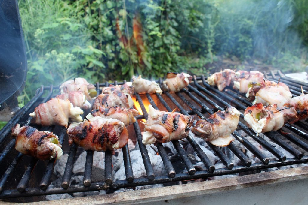 Grill the poppers over hot coals, but keep a close watch and flip often to avoid flare-ups and burned bacon.